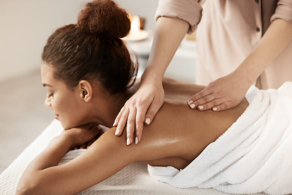 Attractive african girl having massage relaxing in spa salon. Closed eyes.