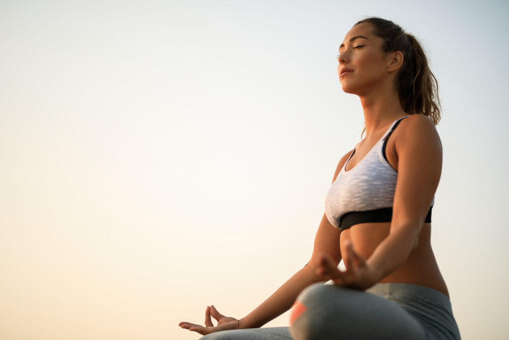 Below view of woman meditating against the sky.